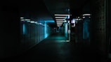 A dark corridor lined with concealed panels emitting faint blue light.