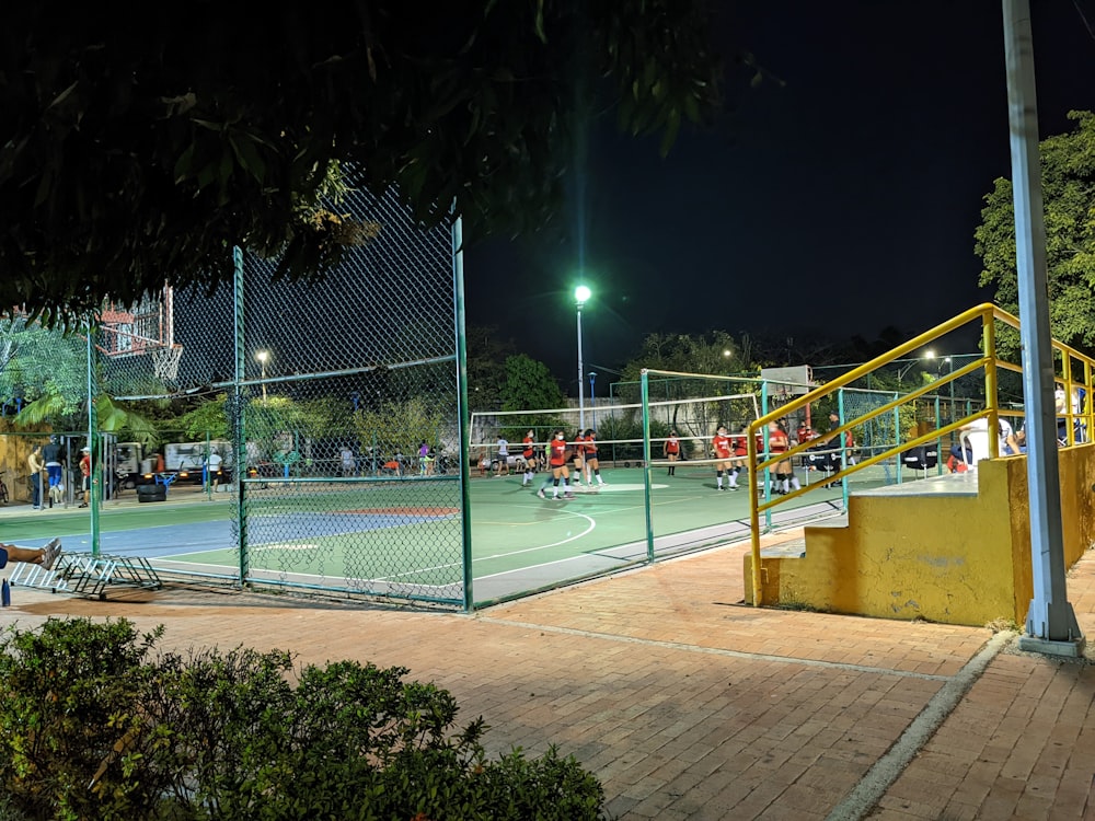 a tennis court at night with people playing