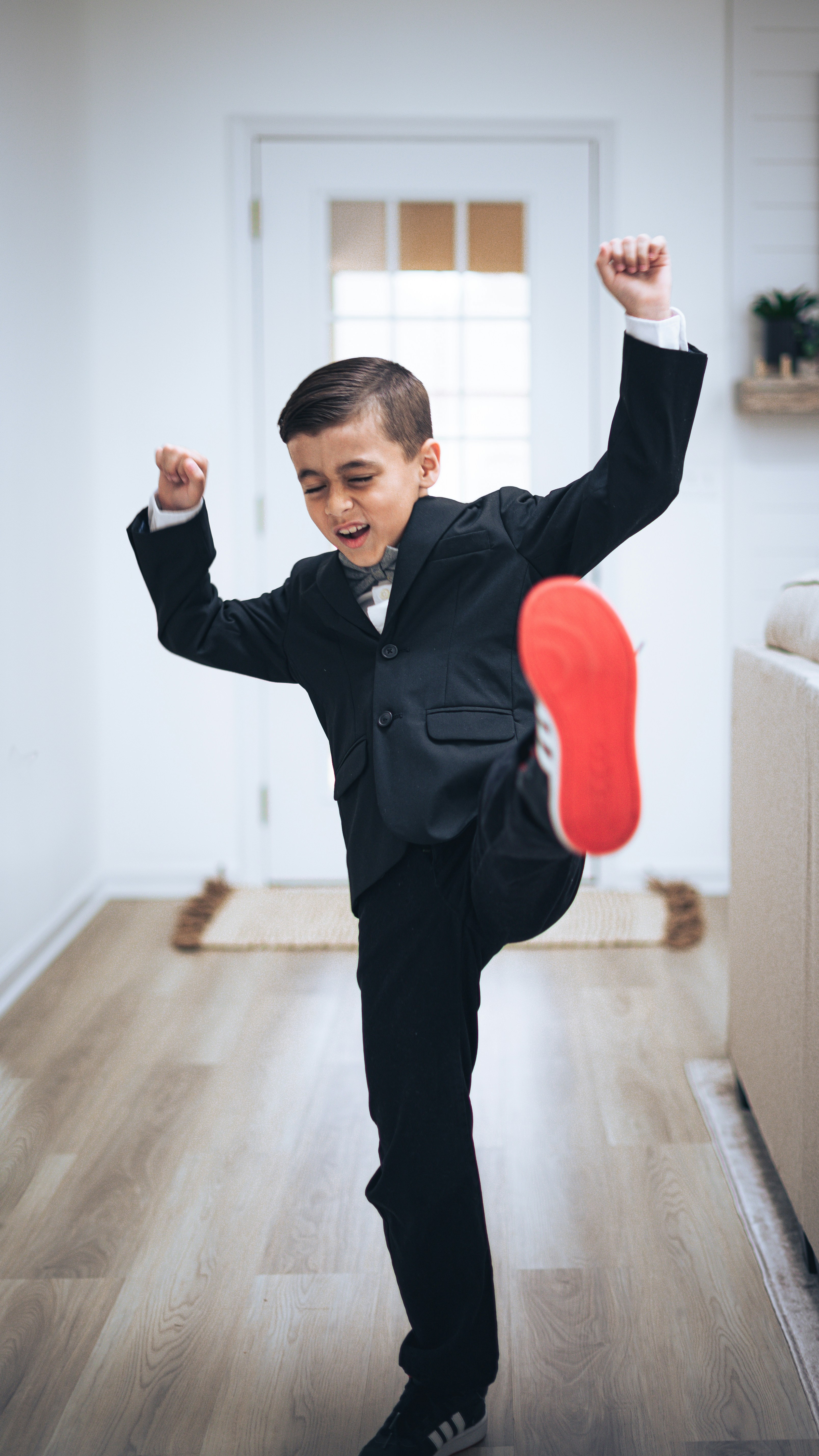 a young boy in a suit is doing a trick