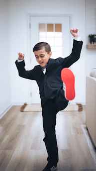 a young boy in a suit is doing a trick