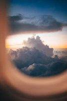 A sunset view from the window of a private jet soaring above the clouds.