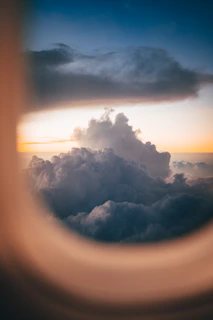 A sunset view from the window of a private jet soaring above the clouds.