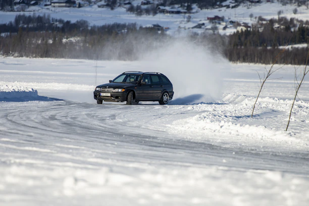 A confident student driver practicing on a safe, snowy driving track in Gothenburg.