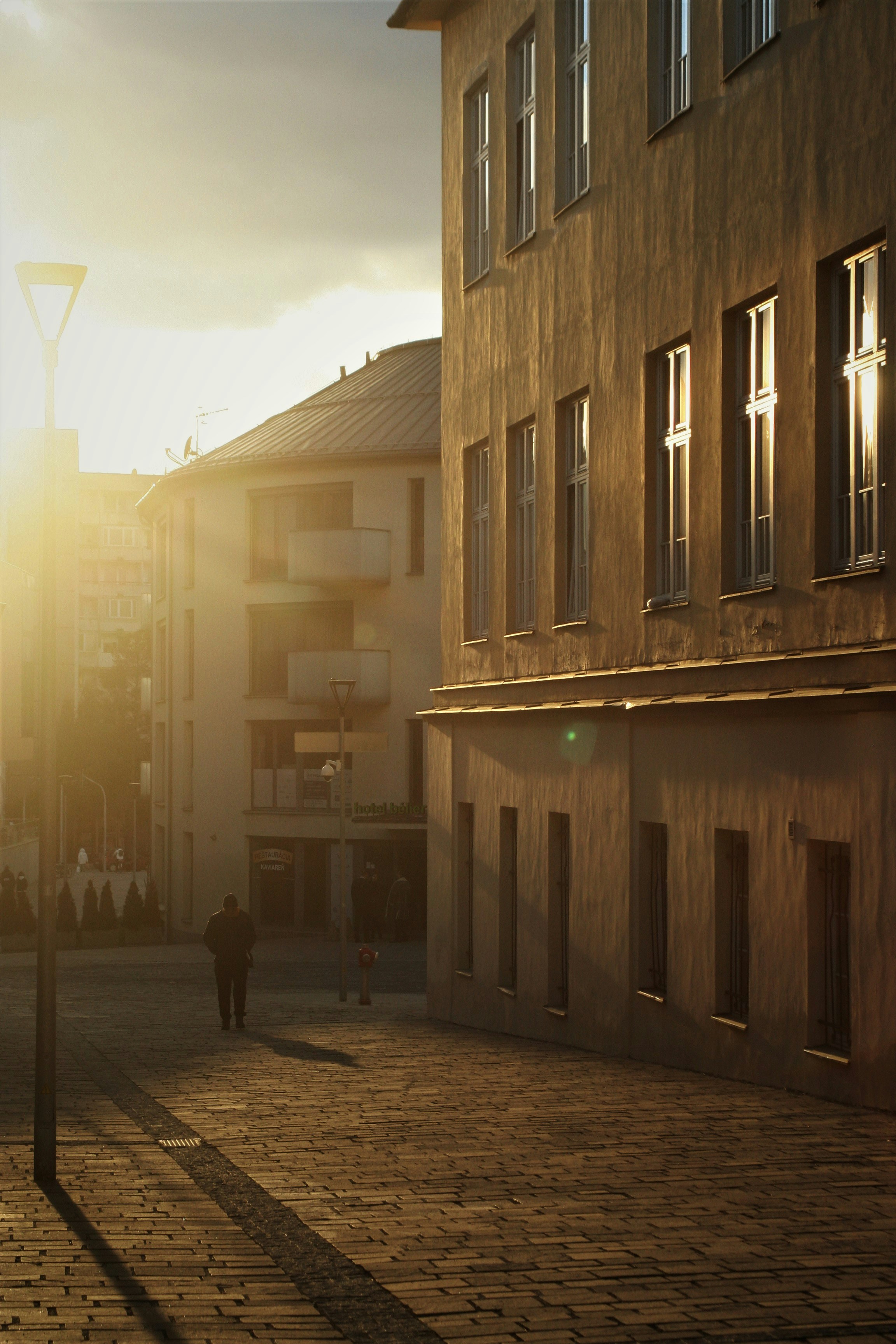 a person walking down a street next to a tall building