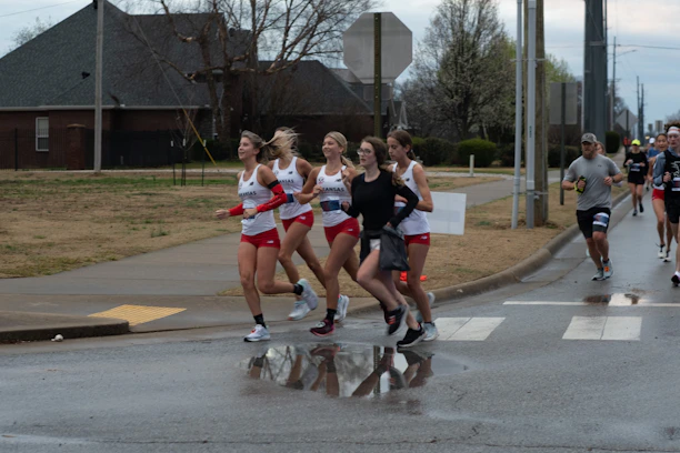 Runners painted in red, blue, and white body paint, symbolizing the three tribes, racing through a rugged mountain trail.