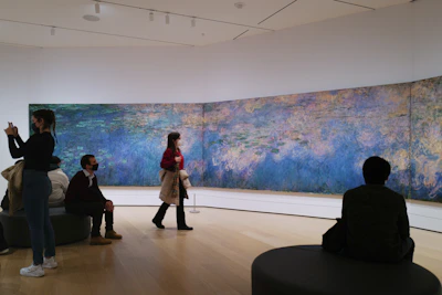 Visitors admiring a large cubist painting in warm ochre and brown hues.