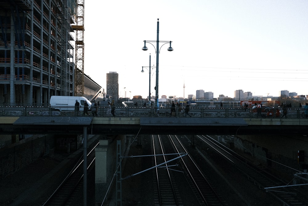 a group of people walking across a bridge over train tracks