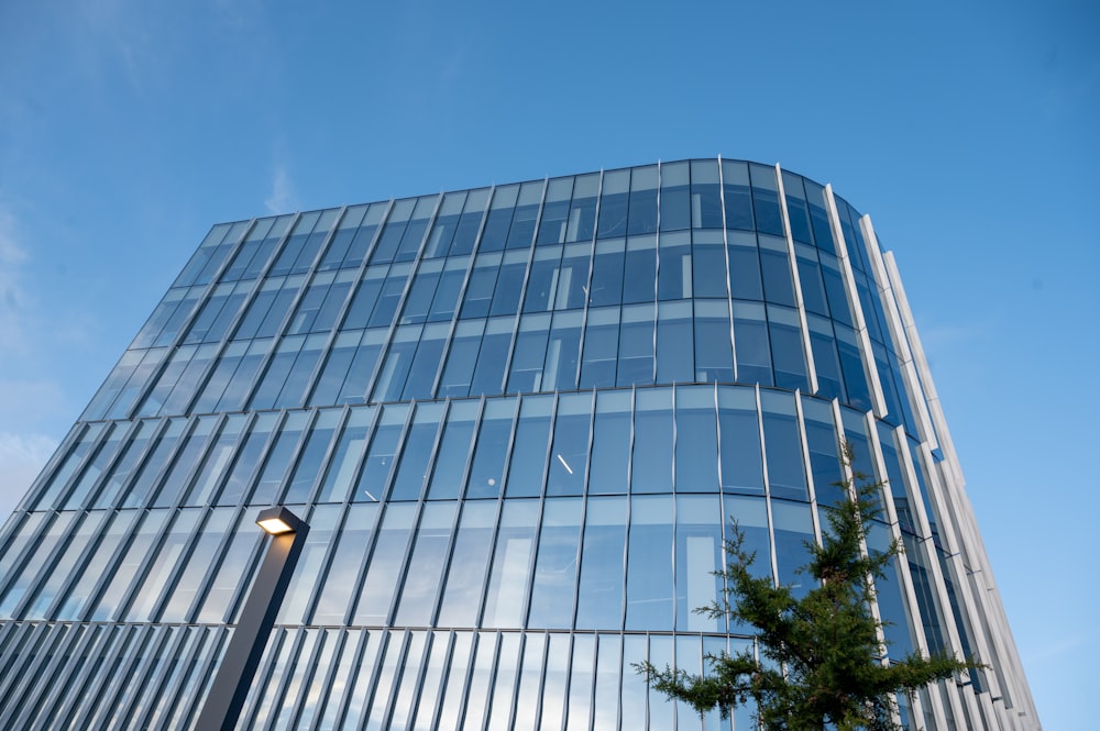 a tall glass building with a street light in front of it