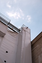 Engineer inspecting a building site with blueprints in hand under a clear blue sky.