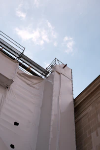 A construction site with scaffolding and building materials under a clear sky.