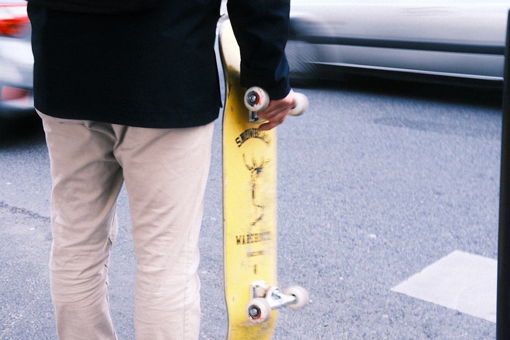 a person holding a skateboard on a city street