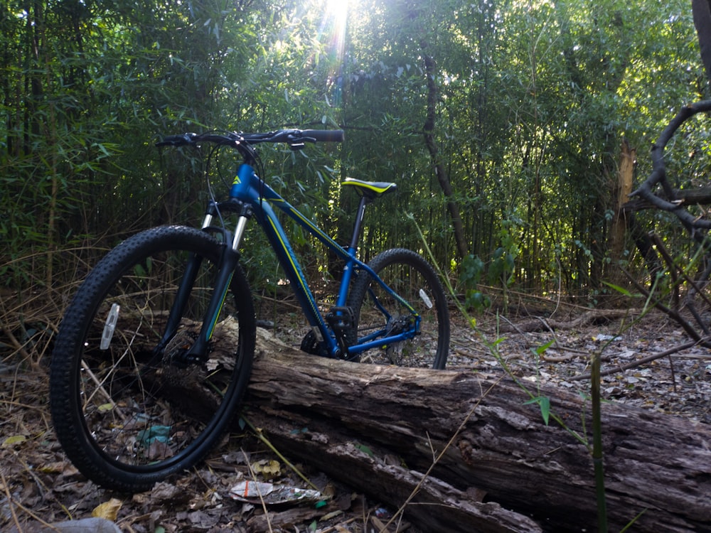 a blue mountain bike parked on a log in the woods