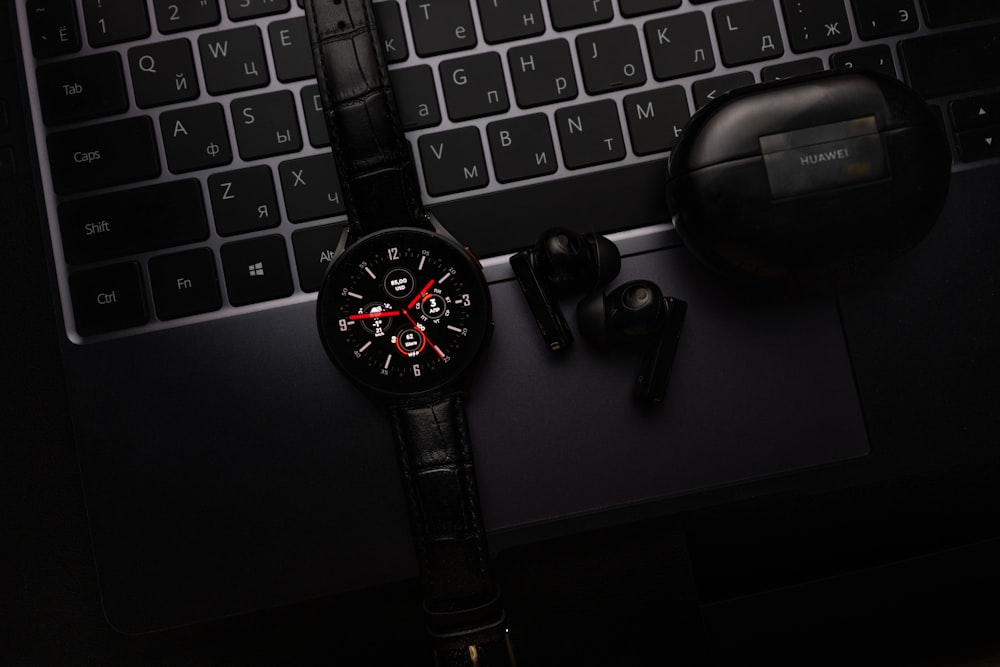 a watch sitting on top of a desk next to a laptop