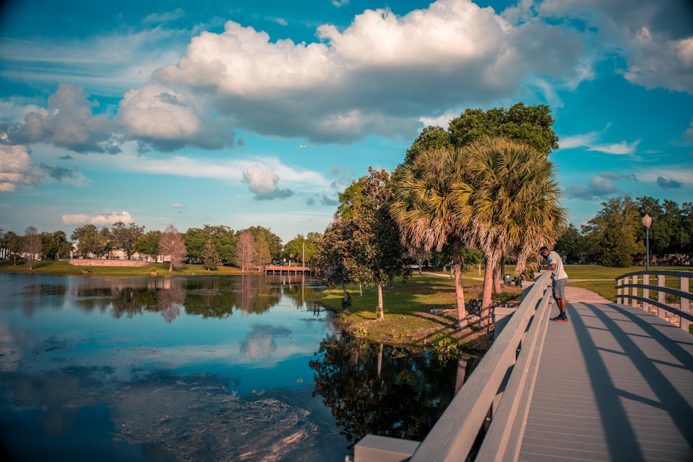 a man riding a skateboard across a bridge over a lake