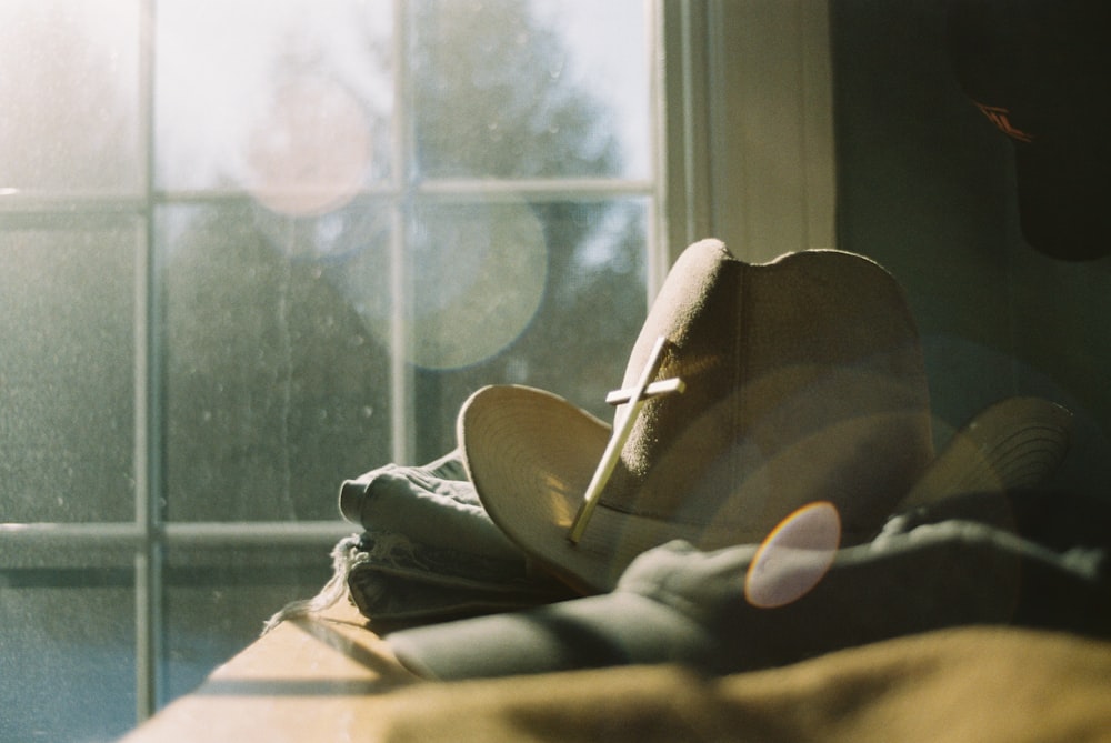 a hat sitting on top of a bed next to a window