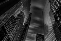 A dramatic black and white shot of city skyscrapers piercing through low-hanging clouds