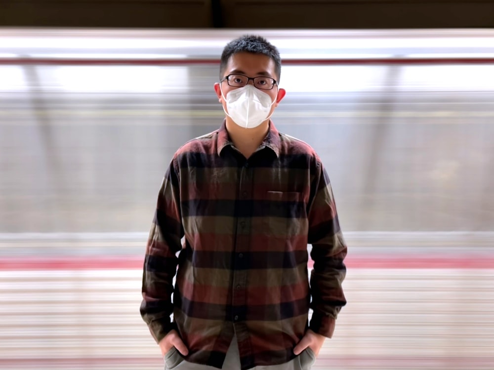 a man wearing a mask standing in front of a train