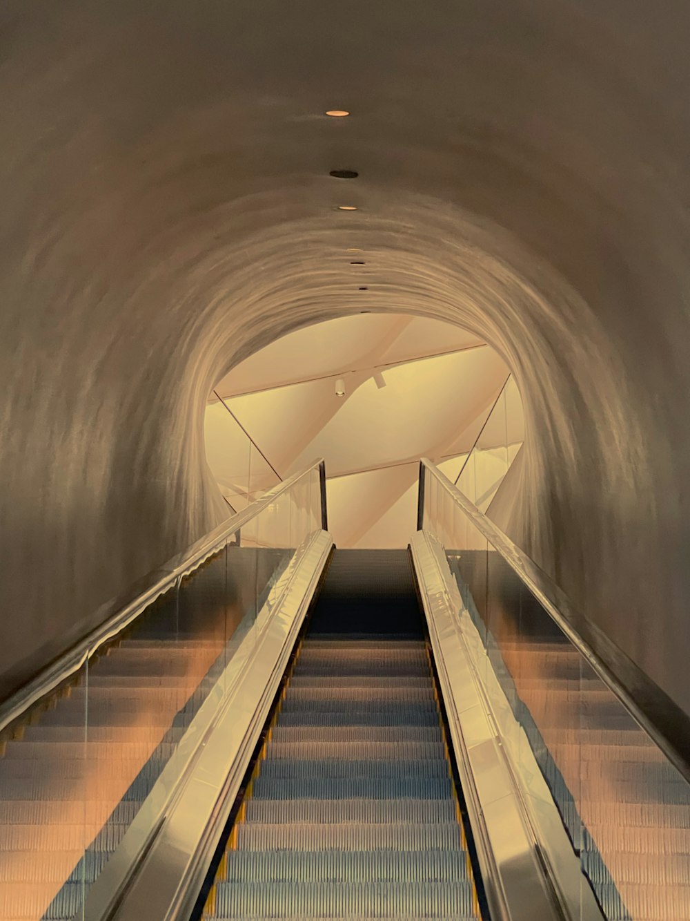 an escalator in a subway station with a light at the end