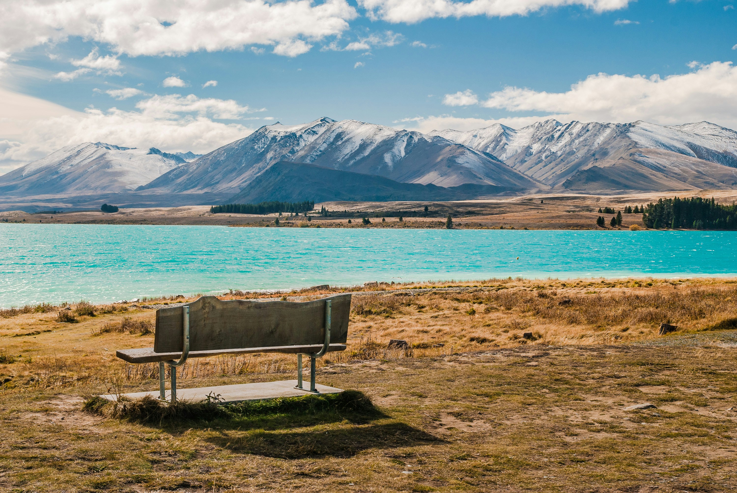 a bench sitting in front of a lake with mountains in the background