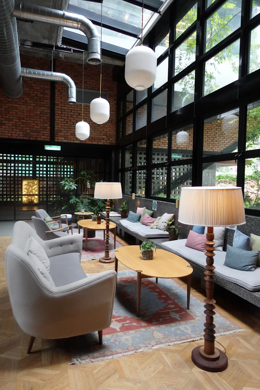 The lobby lounge: linen sofas, pleated lamps and a wall of glass onto the garden
