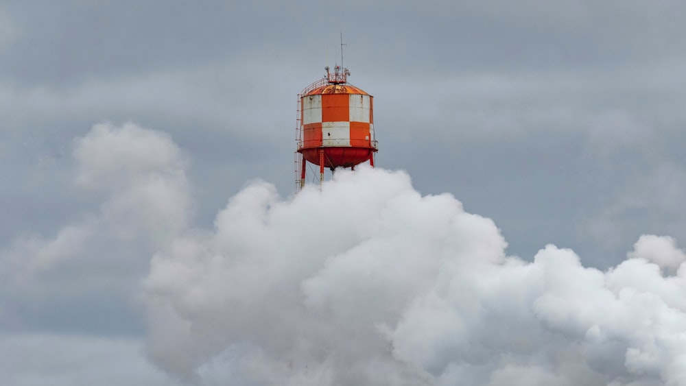 a red and white tower on top of a cloud of smoke