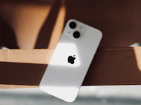 a white iphone sitting on top of a brown belt