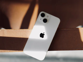 a white iphone sitting on top of a brown belt