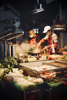 a couple of people cooking food in a kitchen