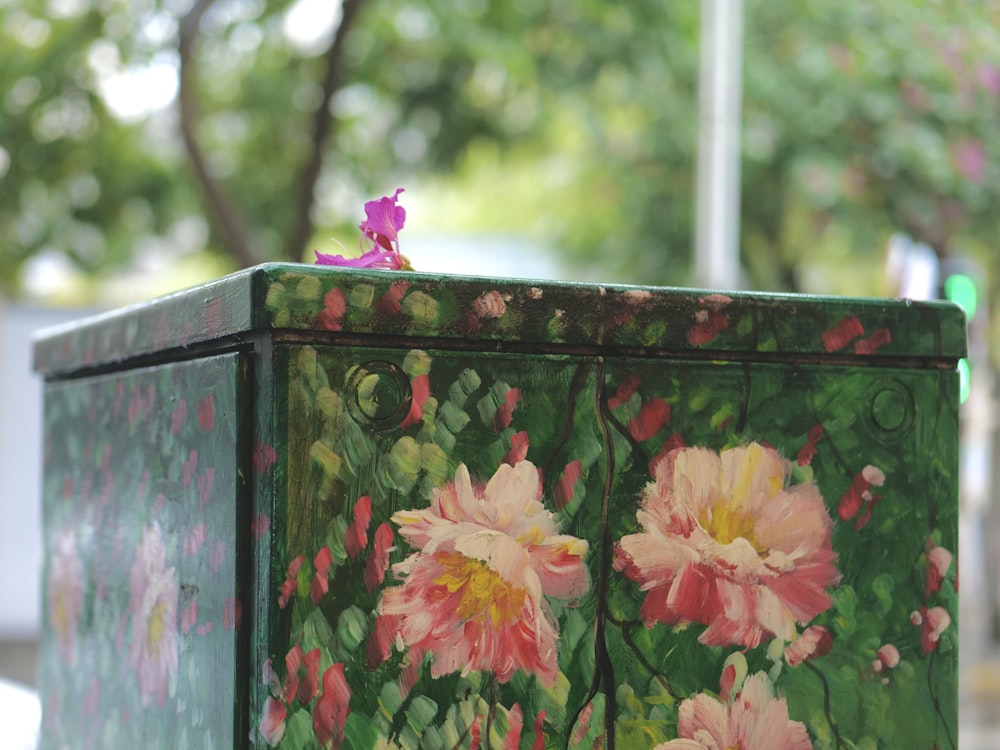 a green box with pink flowers painted on it
