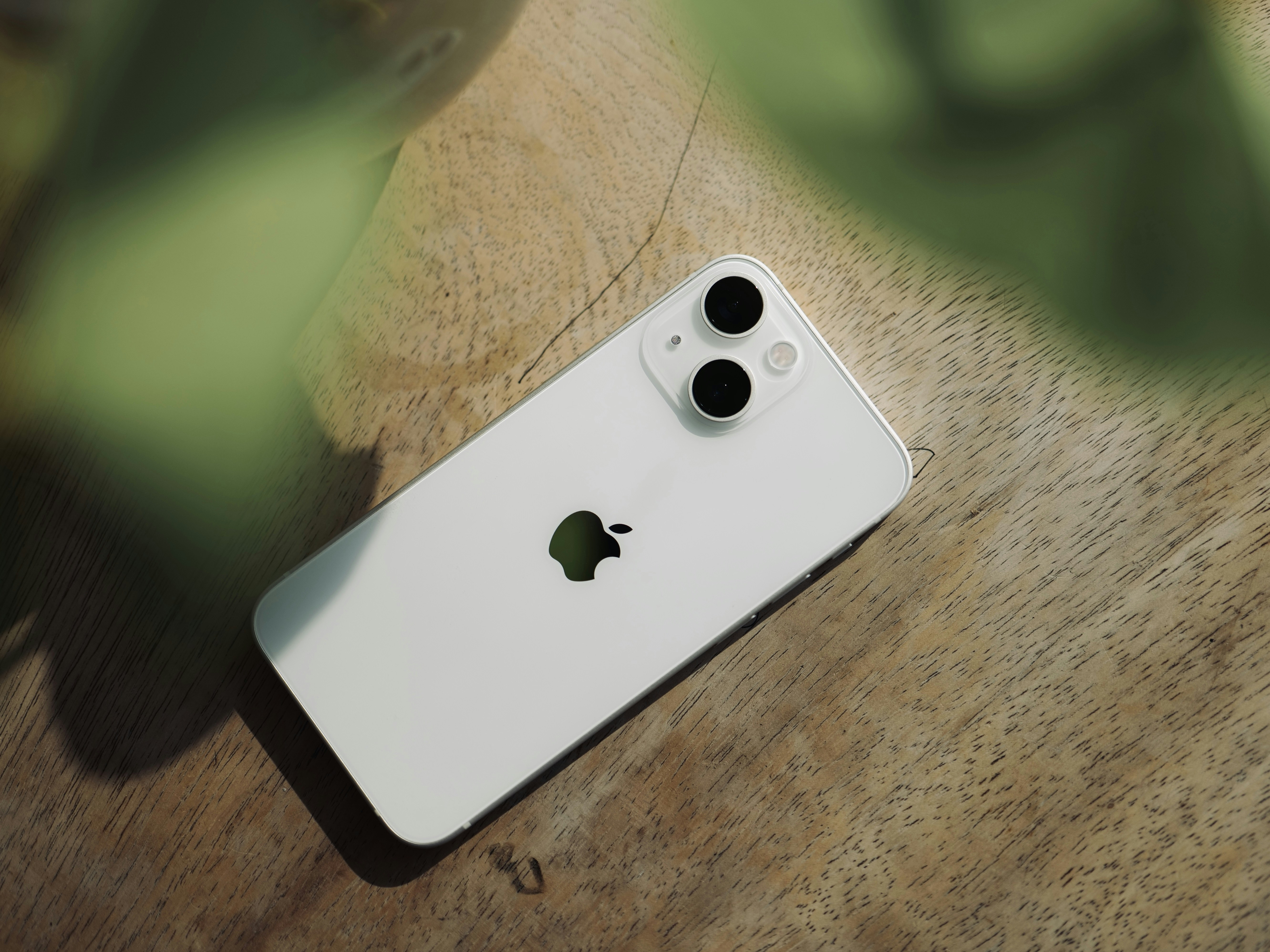 a white iphone sitting on top of a wooden table
