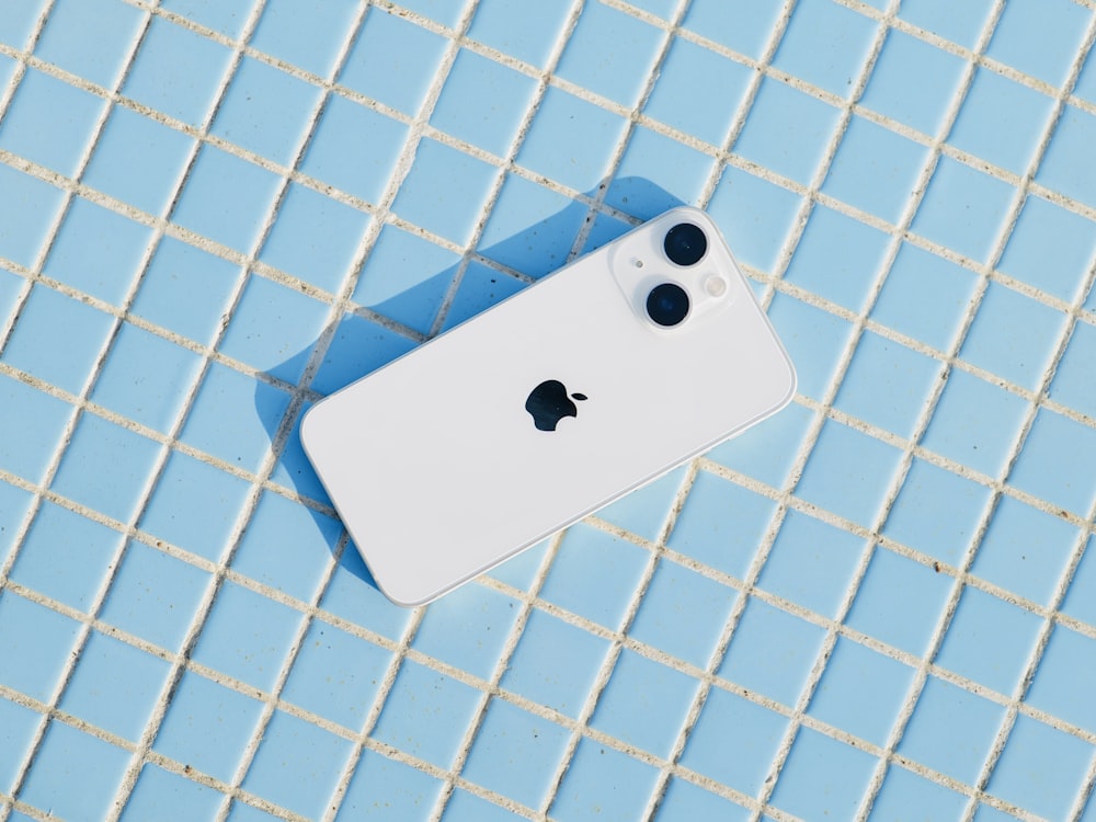 a white iphone sitting on top of a blue tiled floor