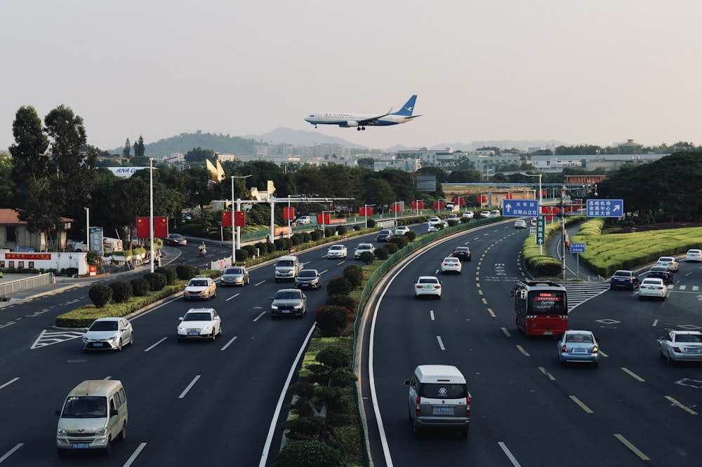 a large jetliner flying over a busy highway