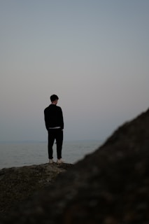 a man standing on top of a rock near the ocean