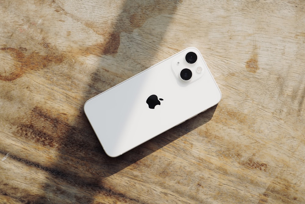 a white iphone sitting on top of a wooden table