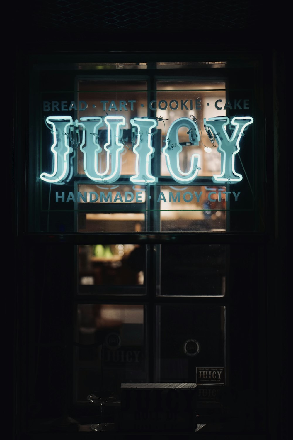 a neon sign that reads juicy hangs in a window