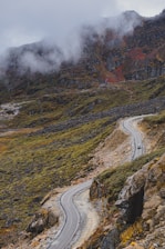 a winding road in the mountains on a cloudy day