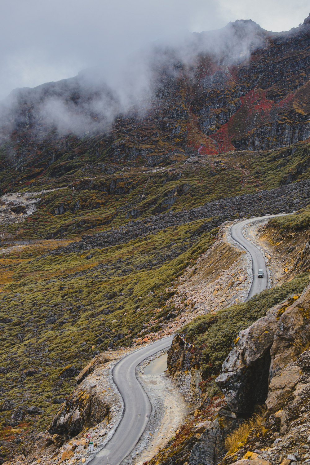 a winding road in the mountains on a cloudy day