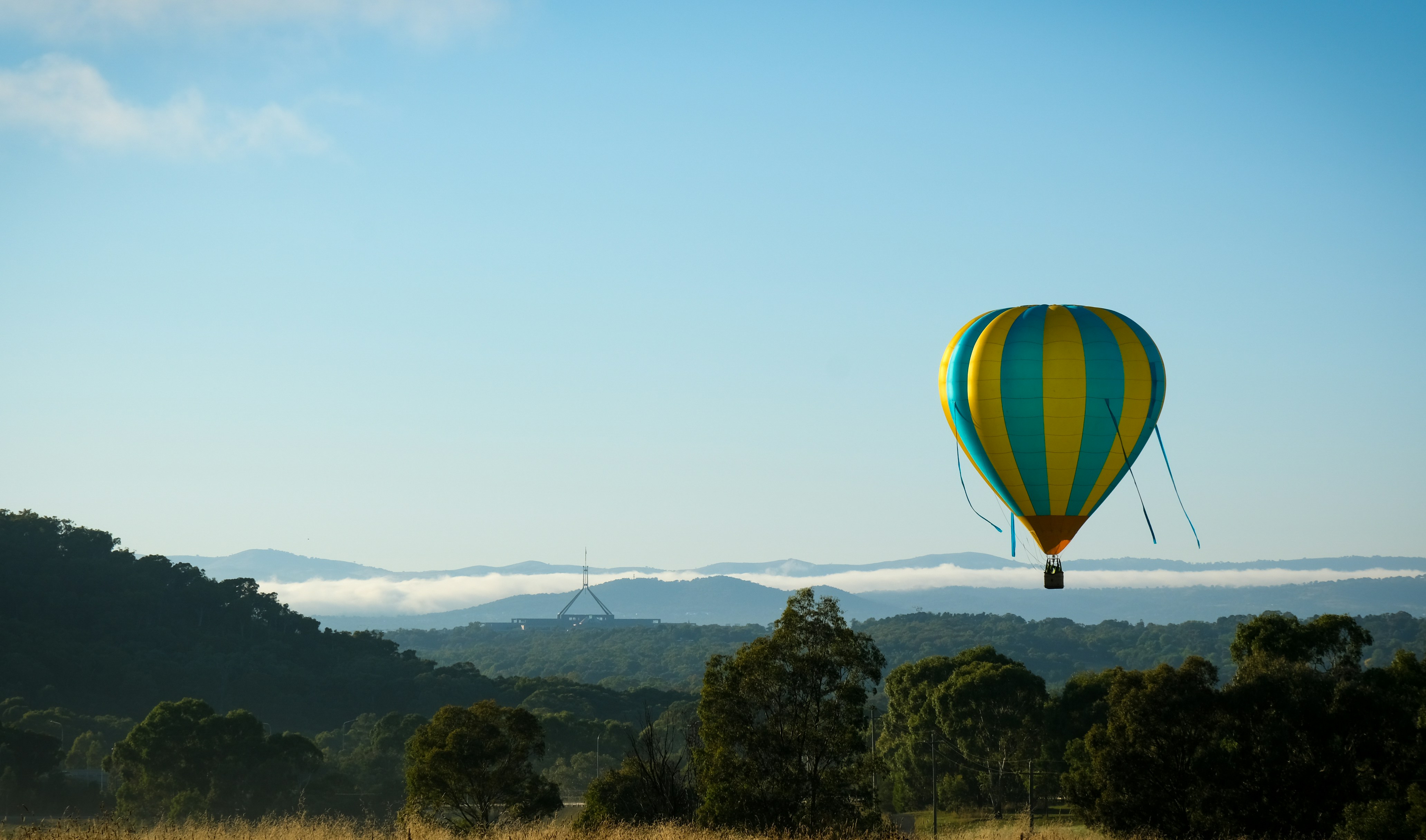 Un globo aerostático volando sobre una exuberante ladera verde