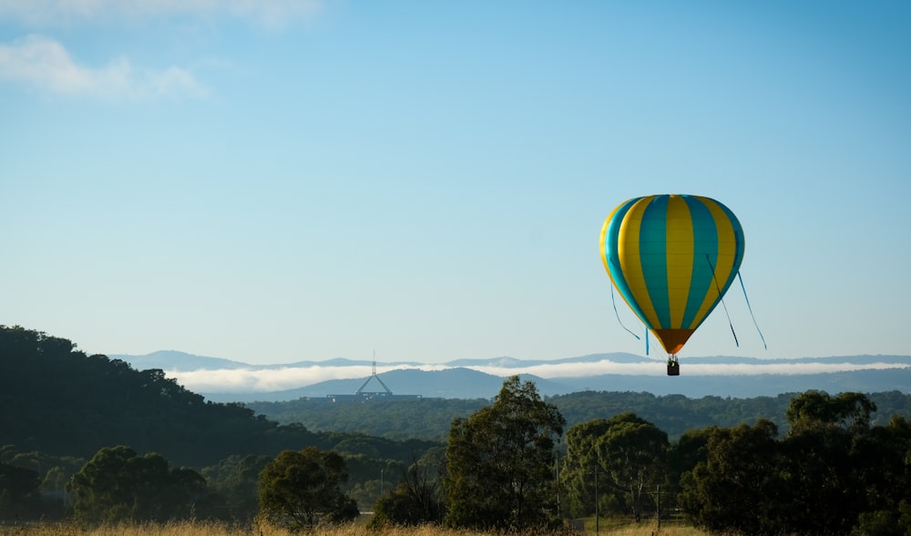 a hot air balloon flying over a lush green hillside