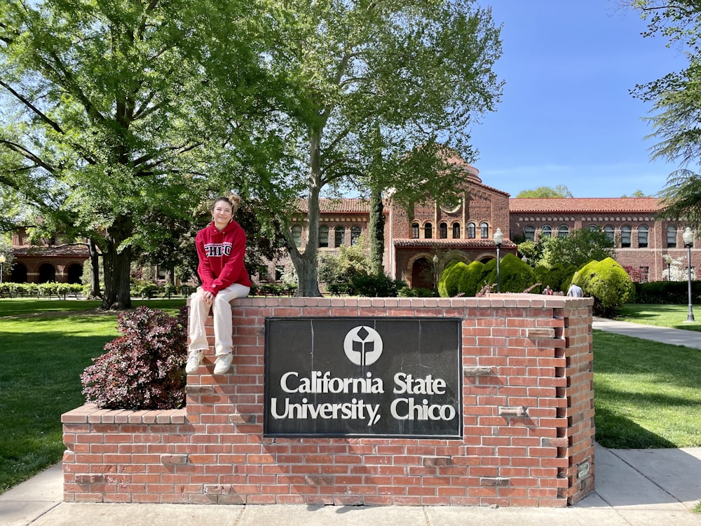 a person sitting on a sign in front of a building