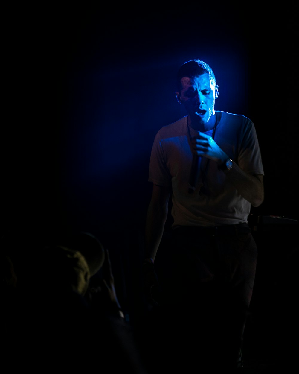 a man standing in the dark with his hands folded
