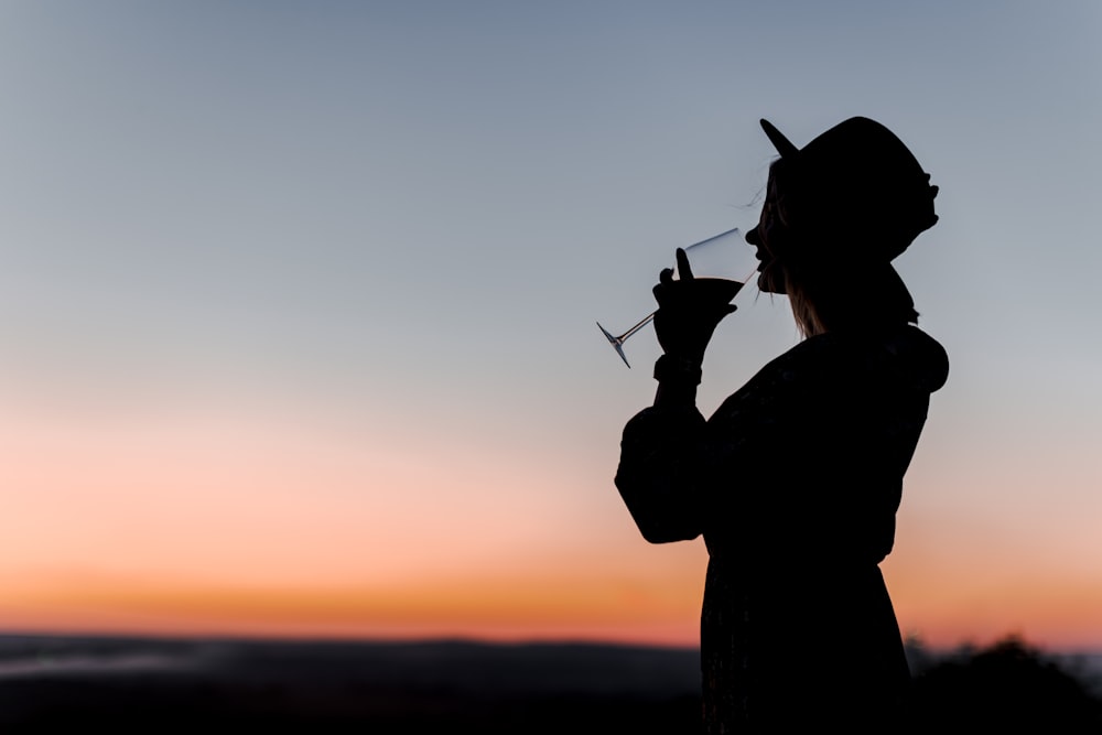 a silhouette of a woman holding a wine glass