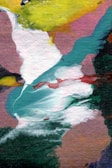 An abstract painting composed of various colors and textures, featuring swirling and overlapping patterns of white, teal, pink, yellow, and green. The brush strokes create a dynamic, flowing composition with a mixture of intense and muted tones.