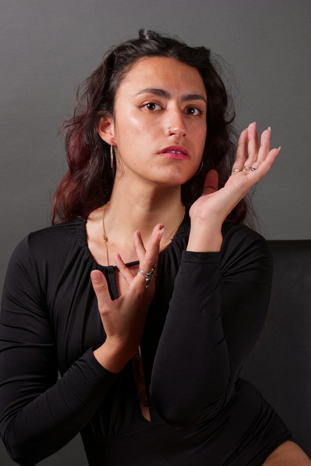 a woman in a black dress holding her hands together