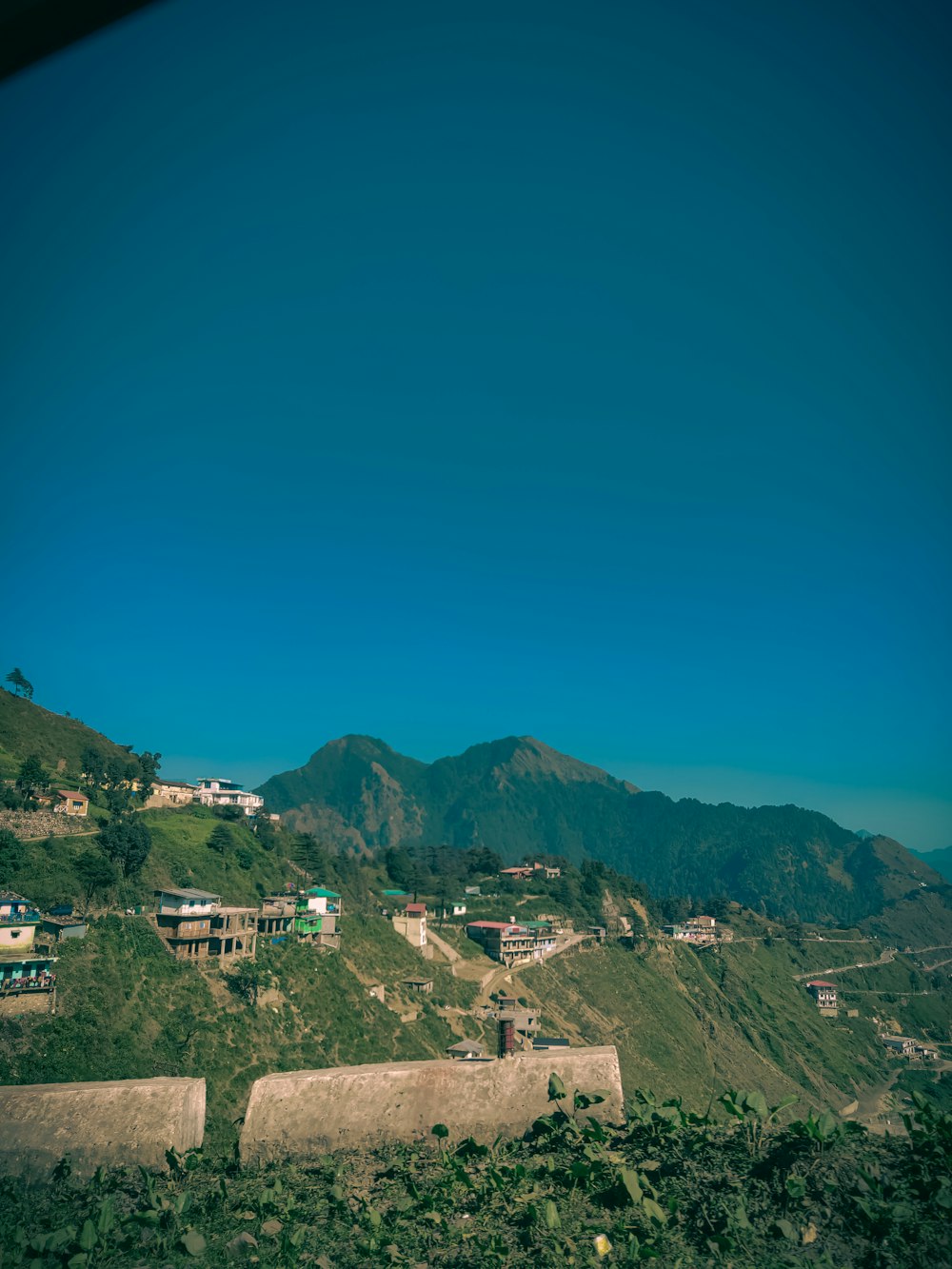a view of a hillside with houses and mountains in the background