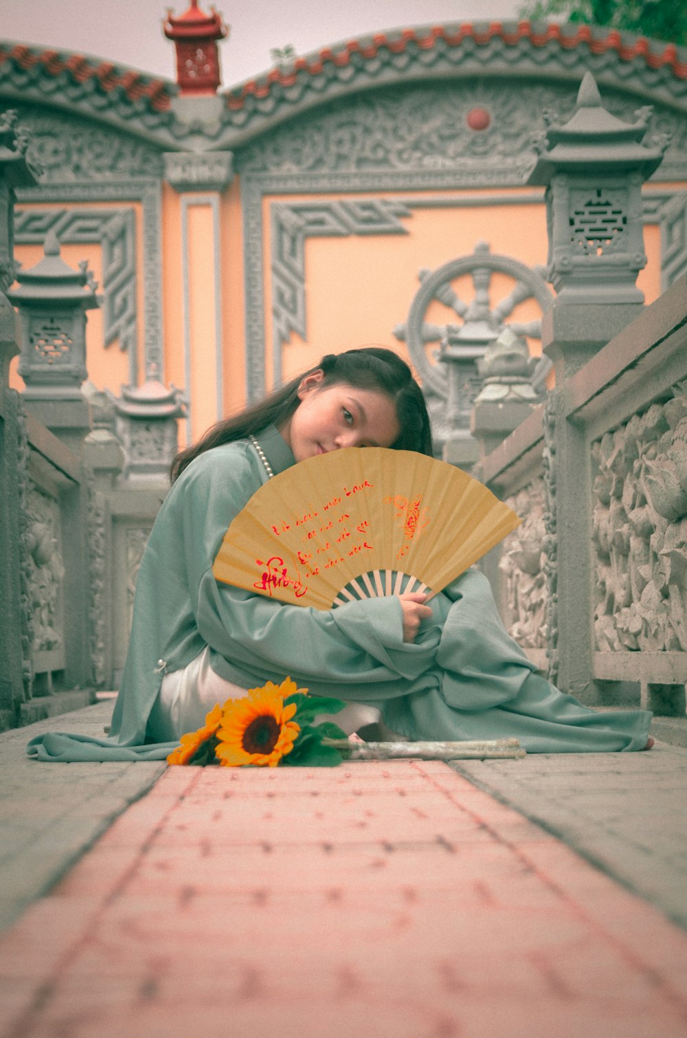 a woman sitting on the ground holding a fan