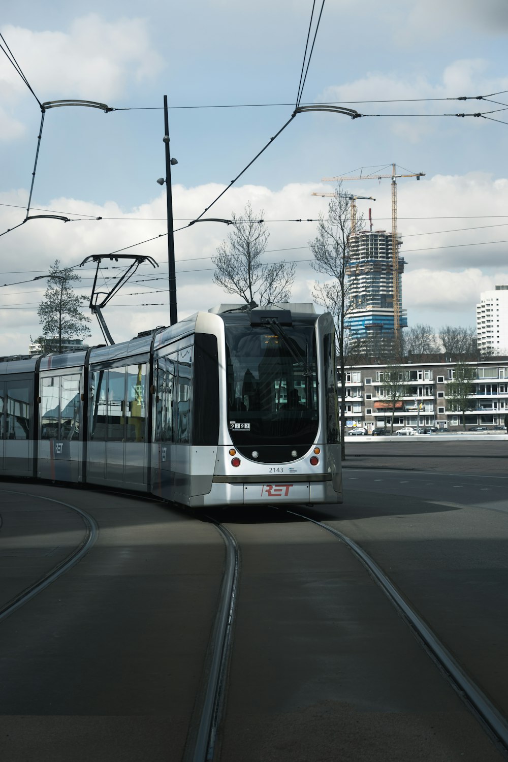 a silver and white train traveling down a street