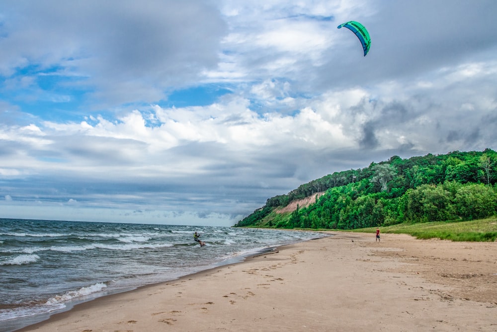 a person flying a kite on top of a sandy beach