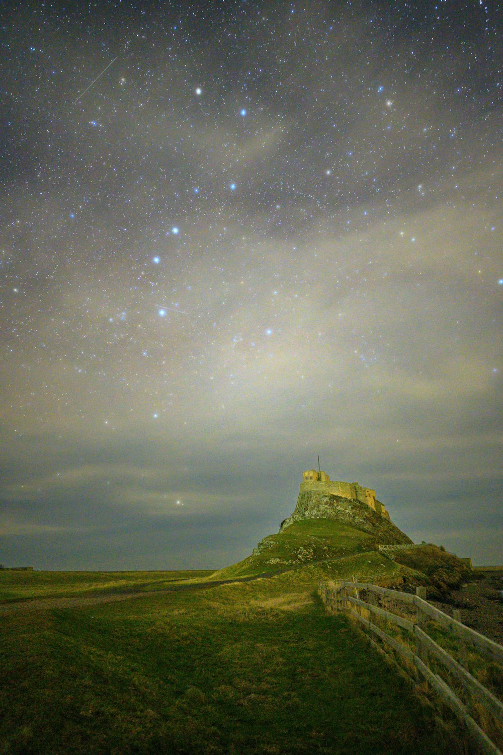 柵のある草が茂った丘の上の夜空