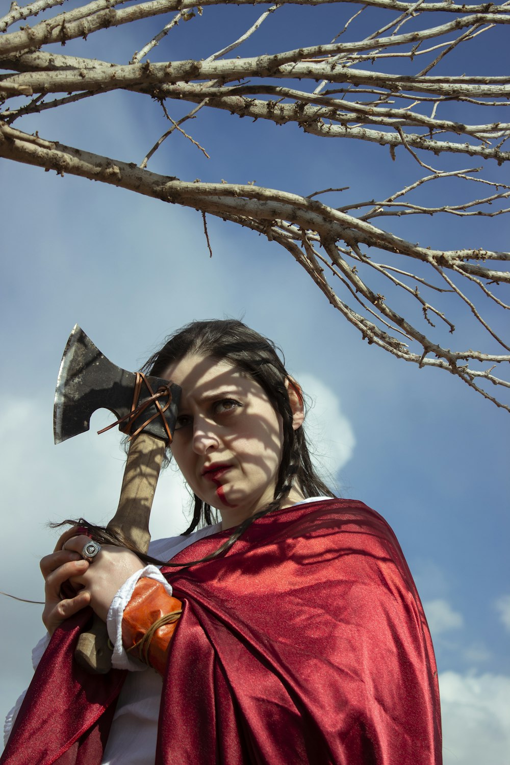 a woman in a red cape holding an axe